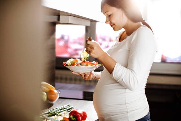 Future mother eating healthy food in the kitchen